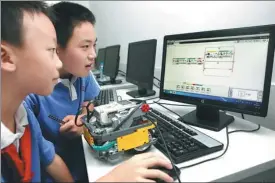  ?? ZHAO YANXIONG / FOR CHINA DAILY ?? Two students create a program for a Lego robot with a computer, at a primary school in Shenzhen.