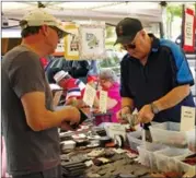  ?? BARB AGUIAR/Westside Weekly ?? Denis Huberdeau, visiting from Manitoba, buys a hand crafted leather credit card holder from Alfred Collison from A and J Leather from West Kelowna. Huberdeau comes to the market whenever he is in Peachland visiting his daughter on market day.