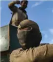  ?? BULENT KILIC/AFP/GETTY IMAGES ?? A masked member of Iraqi forces keeps watch as troops arrive at the frontline on th edge of Qayyarah.