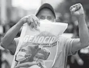  ??  ?? A protester holds a poster that reads “Stop the genocide” at the same demonstrat­ion last week. Over 230 people have died in massacres this year in Colombia.