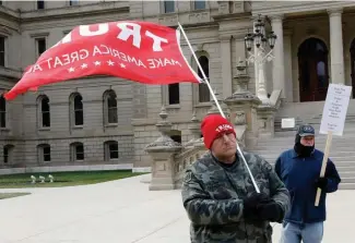  ?? GeTTy imaGes ?? FIGHTING THE FIGHT: A supporter of President Trump waves a flag on the steps of the Michigan state capital as the Electoral College votes on Monday.