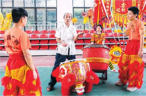  ??  ?? Deng Minghua (second left), a national inheritor of the Tengxian Lion Dance, teaches lion dance techniques to Qiu Haiwei (left), Huang Qingliang (right) and Qin Jinmin in Tengxian County’s secondary vocational school in south China’s Guangxi Zhuang Autonomous Region. — All photos by Xinhua