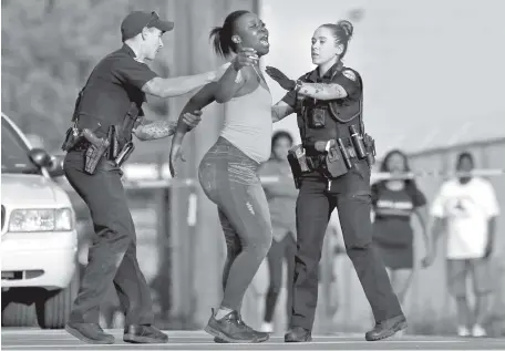  ?? STAFF PHOTO BY C.B. SCHMELTER ?? Two police officers try to comfort a woman and move her behind the police tape at the scene of a fatal shooting at the intersecti­on of Central Avenue and West 38th Street on Sunday.