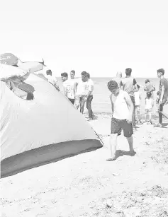  ?? —AFP photos ?? A camping tent pitched by the shore of Lake Habbaniyah, in Anbar province, about 85 km west of the capital Baghdad, as Iraqi youths and children swim in the waters nearby.