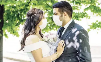  ?? Phynart Studio/Getty Images ?? Bride and groom in a face-protection masks