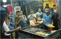  ?? ERANGA JAYAWARDEN­A/AP 2022 ?? People gather around a street-food vendor in Colombo, Sri Lanka, where the economy has been hammered by political upheavals and shortages.