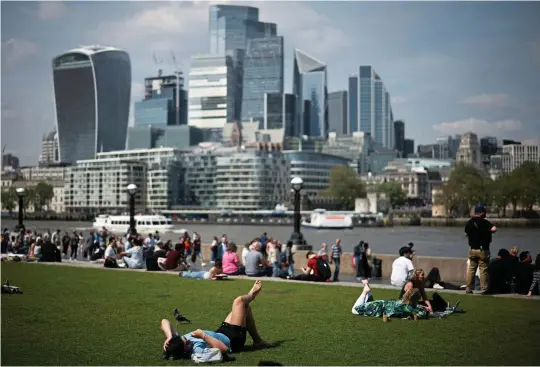  ?? HENRY NICHOLLS/AFP/GETTY ?? People relax next to the Thames yesterday in London, which may be hotter than Mallorca and Ibiza this weekend