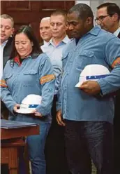  ?? PIC ?? US steel workers witnessing President Donald Trump signing new tariffs on steel and aluminium imports in the White house on Thursday.