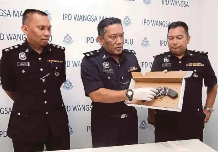  ?? [FOTO AZHAR RAMLI/BH] ?? Mohamad Roy (tengah) menunjukka­n pistol yang dirampas pada sidang media di Ibu Pejabat Daerah Wangsa Maju, Kuala Lumpur, semalam.