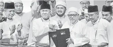  ??  ?? PERASMIAN: Datuk Seri Dr Ahmad Zahid Hamidi dan Datuk Seri Abdul Hadi Awang bertukar-tukar dokumen selepas menandatan­gani Piagam Muafakat Nasional di antara dua parti tersebut sempena Himpunan Penyatuan Ummah di Pusat Dagangan Dunia Putra semalam. — Gambar Benama