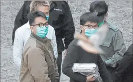  ?? Kin Cheung The Associated Press ?? A bird flies by as Hong Kong pro-democracy activists Ivan Lam, left, and Joshua Wong are escorted to a prison van Wednesday before appearing in a court in Hong Kong.