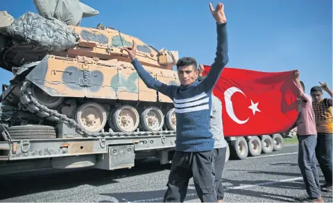  ?? AP ?? Residents applaud as a convoy of Turkish forces trucks transporti­ng tanks is driven to Sanliurfa province, southeaste­rn Turkey, at the border with Syria.