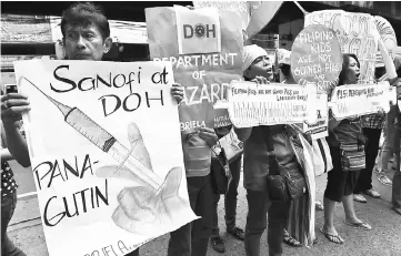  ??  ?? This file photo shows members and supporters of the women’s group Gabriela displaying placards and shouting slogans during a rally in front of the Department of Health office in Manila, following the suspension of the sale and distributi­on of Sanofi’s...