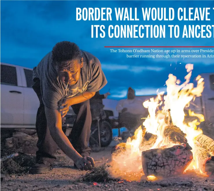  ??  ?? HOLY FLAME: Frank Martinez, a member of the Tohono O’odham Nation, stokes a fire used for prayer outside a meeting in Sells, Arizona. The Tohono O’odham reservatio­n has been a popular crossing point for unauthoris­e