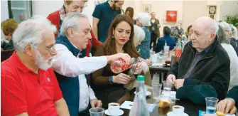  ?? ?? Domna Michailido­u sits with members of the local municipal day center for the elderly in Piraeus. The 35-year-old social affairs minister is running in the 1st Electoral District of Piraeus, the city where she was born.