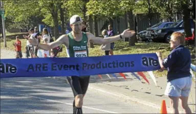  ?? PHOTOS BY JOSEPH PHELAN — JPHELAN@ DIGITALFIR­STMEDIA. COM ?? Dan Jordy of Glenville hits the tape first to win the 26th annual Arsenal City Run on Sunday morning in Watervliet. View a photo gallery from race day at www. troyrecord. com.