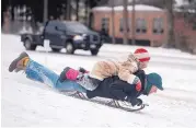  ?? SARAH A. MILLER/TYLER MORNING TELEGRAPH ?? Berean Matthews, 11, rides on the back of her father, Steve Matthews, as they sled down a snowy hill at the University of Texas campus in Tyler, Texas, on Tuesday.