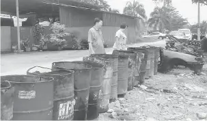  ?? — Gambar Bernama ?? BENTENG: Tham, (kiri) menunjukka­n tong minyak terpakai yang digunakan sebagai benteng bagi menghalang limpahan air laut memasuki kawasan rumah akibat fenomena air laut pasang besar semalam.