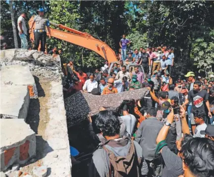  ?? Chaideer Mahyuddin, AFP/Getty Images ?? Residents and members of a search-and-rescue team carry the body of an earthquake victim in Pidie Jaya, Indonesia. At least 97 people were killed and dozens are feared trapped in rubble after Wednesday’s temblor.