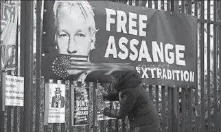  ?? LONDON
-REUTERS ?? A supporter of WikiLeaks founder Julian Assange posts a sign on the Woolwich Crown Court fence, ahead of a hearing to decide whether Assange should be extradited to the United States, in London, Britain.