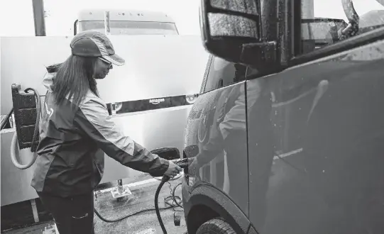  ?? CLARENCE TABB JR. TNS ?? Kayla Dudley, 24, driver associate at Amazon, unplugs the electrical power cable from her new Amazon EV delivery truck, which is on Rivian's truck platform, at Pontiac Amazon Fulfillmen­t Center in Pontiac, Michigan, on April 2.