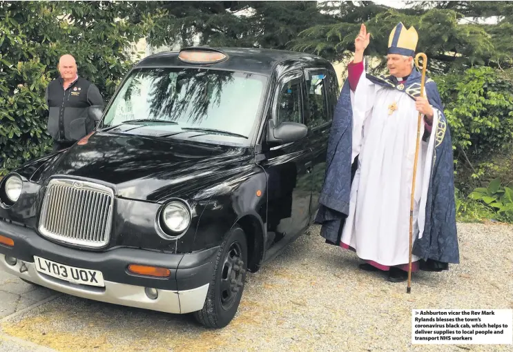  ??  ?? > Ashburton vicar the Rev Mark Rylands blesses the town’s coronaviru­s black cab, which helps to deliver supplies to local people and transport NHS workers