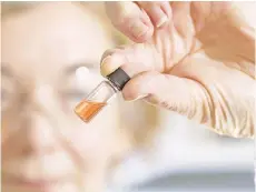  ?? — AFP photo ?? This handout photo from theAustral­ian National University (ANU) shows biogeochem­istry lab manager Janet Hope from the ANU Research School of Earth Sciences holding a vial of coloured porphyrins, a pink coloured liquid, in Canberra.