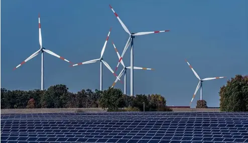  ?? ?? Des éoliennes tournent derrière un parc solaire à Rapshagen, en Allemagne.