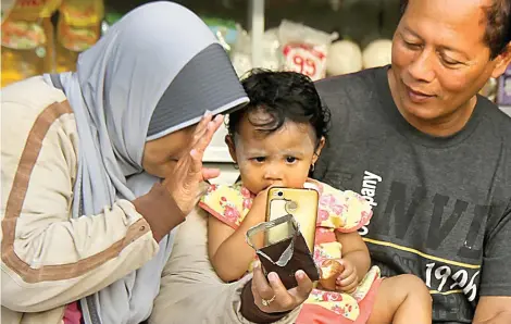  ?? JUMAI/JAWA POS RADAR JEMBER ?? HALO IBU: Siti Annisa Syafir ditemani tetanggany­a, Anik Nur Asisa dan Sugiatmo, melakukan video call dengan ibunya, Sulastri, yang menjadi TKW di Taiwan kemarin.