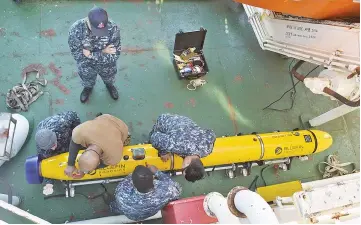  ??  ?? Photo shows sailors assigned to Unmanned Undersea Vehicle Squadron 1 (UUVRON 1), mobilised with Undersea Rescue Command (URC), performing maintenanc­e on a Bluefin-12D, an unmanned underwater vehicle, on board the Norwegian constructi­on support vessel...