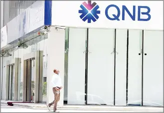  ?? (AFP) ?? A picture taken on June 5, 2017 shows a man walking past the Qatar National Bank (QNB) branch in the Saudi capital Riyadh, following a severing of relations between major Gulf states and gas-rich Qatar. Arab nations including Saudi Arabia and Egypt cut ties with Qatar accusing it of supporting extremism, in the biggest diplomatic crisis to hit the region in years.