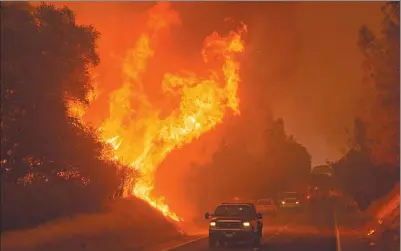  ?? JOSH EDELSON / AGENCE FRANCE-PRESSE ?? Motorists drive past flames from the “Wall Fire” along Forbestown Road in Oroville, California on Saturday. The first major wildfires after the end of California's five-year drought raged across the state.