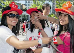  ?? JENELLE SCHNEIDER/PNG FILES ?? A trio of celebrants get into the Canada Day spirit with flags, hats, T-shirts and temporary tattoos.