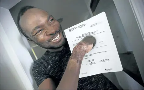  ?? JOHN WOODS/THE CANADIAN PRESS ?? Seidu Mohammed smiles as he shows off his refugee claim acceptance letter in Winnipeg on Thursday.