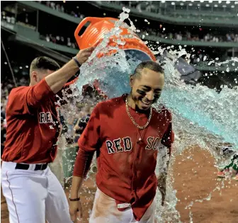  ?? STaff phoToS By ChRISTophE­R EVaNS ?? POWERFUL DISPLAY: Mookie Betts gets a bath after belting his walkoff home run leading off the bottom of the 10th inning to push the Red Sox to a 4-3 victory against the Minnesota Twins last night at Fenway; Betts’ blast (bottom left) came after Rafael...