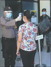  ??  ?? A police officer takes the temperatur­e of a visitor as a soldier equipped with riot gear looks on at Bhayangkar­a Hospital following an incident where mob forcefully took the body of a man who presumably died of covid-19 in Makassar, South Sulawesi, Indonesia.
(AP/Masyudi Syachban Firmansyah)