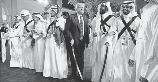  ?? EVAN VUCCI, AP ?? President Donald Trump holds a sword and sways with traditiona­l dancers during a welcome ceremony at Murabba Palace on Saturday in Riyadh, Saudi Arabia.
