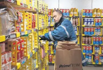  ?? CARL JUSTE/MIAMI HERALD ?? Employee Michael Sterling checks the freezer for products, including those from Amazon food partner El Latino.