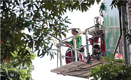  ?? HARIYANTO TENG/JAWA POS ?? RAPIKAN POHON: Petugas DKRTH menaiki Bronto Skylift untuk memotong dahan-dahan pohon yang terlampau tinggi di Jalan Mayjen Sungkono kemarin.