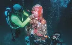  ?? New York Times News Service ?? Divers clean an underwater Virgin Mary statue off the coast of Boho. Locals have placed religious statues under the sea to help fend off dynamite fishing.