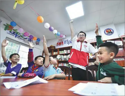  ?? HUANG XIAOBANG / XINHUA ?? Wu Yingqi, a volunteer from Zhengzhou University, shares a light moment on May 5 with students in a classroom in a new community in Rongshui Miao autonomous prefecture, Guangxi Zhuang autonomous region. As part of the local government’s efforts to improve people’s lives, students who have moved with their families from mountainou­s areas to new communitie­s are organized to take part in various classes with help from college students.