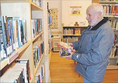  ?? ERIC MCCARTHY/TC MEDIA ?? Gary Rochford of Alberton searches out reading materials on the shelves of the Alberton Public Library, now located in the Old Stone Station.