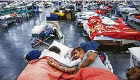  ?? Michael Ciaglo / Staff photograph­er ?? Tammy and Christophe­r Dominguez sleep on cots at the George R. Brown Convention Center, where nearly 10,000 people took shelter in Harvey’s wake.