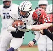  ?? Charles Krupa / Associated Press ?? Yale quarterbac­k Griffin O’Connor, left, tries to elude Harvard linebacker Cameron Kline (52) at Fenway Park in Boston in 2018.