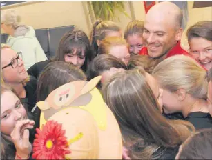  ?? JASON MALLOY/THE GUARDIAN ?? The Scotiabank Reds under-18 girls softball team give coach Jeff Ellsworth a group hug after he arrived Sunday at the Charlottet­own Airport.