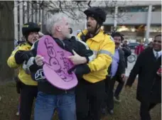  ??  ?? Uber supporter Mark Harrison is escorted away by police officers after being swarmed by cab drivers protesting against Uber at city hall.