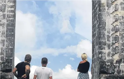  ?? Picture: AP. ?? Visitors at a temple in Karangasem, Indonesia, watch the volcano erupting.