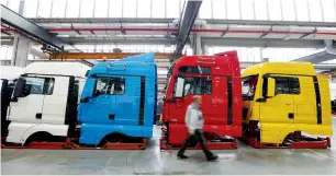 ?? — Reuters ?? A man walks past driver cabins in a truck production plant in Munich. The United States accounts for roughly 10 per cent of Germany’s sales abroad.