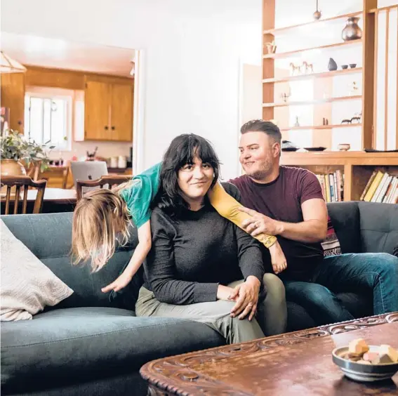  ?? CAROLYN FONG/THE NEW YORK TIMES ?? Maria Rapier, center, with her husband Beau and their daughter Guinevere at home in Oakland, California.
