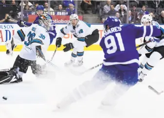  ?? Nathan Denette / Associated Press ?? The Maple Leafs’ John Tavares scores against Sharks goalie Aaron Dell. Tavares had two goals, and Auston Matthews also scored twice and added an assist in Toronto’s victory.
